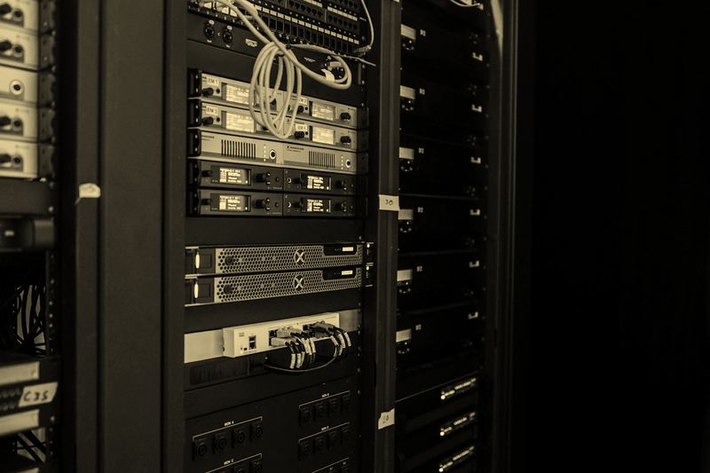 An open server rack with patch cables and equipment in a plainly lit server room, no people
